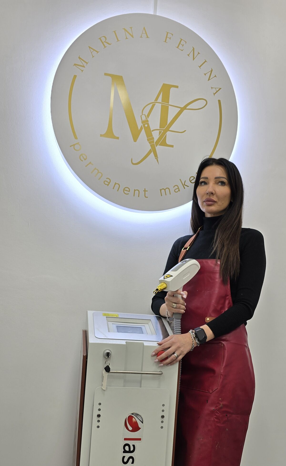 Марина Фенина с неодимовым лазером Lasertech H2 на фоне логотипа студии PERMANENT STUDIO